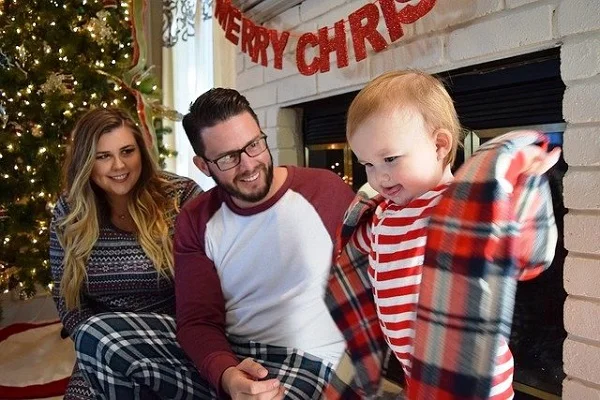 une famille qui décore un sapin de noel dans un salon